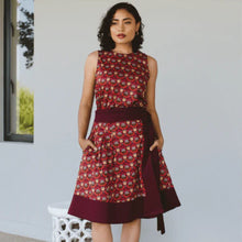 Load image into Gallery viewer, Woman wearing a red and brown patterned dress standing against a light background