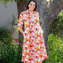 Load image into Gallery viewer, Woman wearing a colorful floral dress standing outdoors near a tree