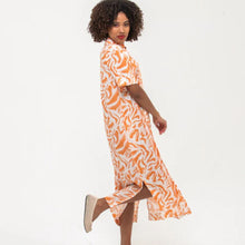 Load image into Gallery viewer, Woman wearing an orange and white patterned dress on a white background