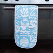 Load image into Gallery viewer, Blue oven mitt with white patterns hanging on an oven handle.