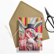 Load image into Gallery viewer, Greeting card with a flamingo wearing a top hat on a colorful striped background, with a brown envelope and scissors in the background.

