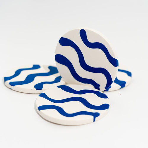 Four ceramic coasters with blue wave pattern on a white background