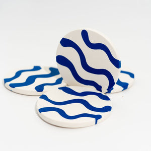 Four ceramic coasters with blue wave pattern on a white background