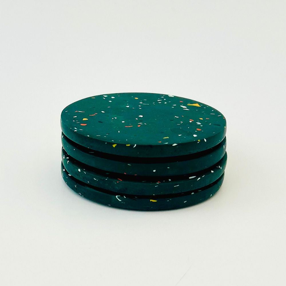 Set of four green speckled coasters on a white background