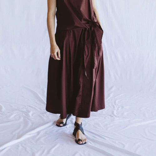 Person wearing a brown dress standing on a white background