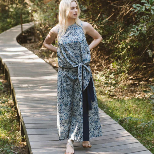 Woman in a floral skirt & matching top standing on a wooden path in a natural setting