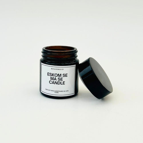 Candle in a black jar with a humorous expression about Eskom on a white label