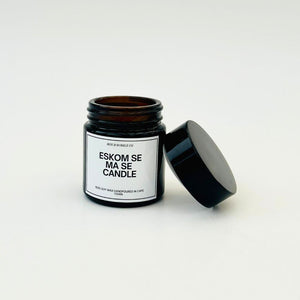 Candle in a black jar with a humorous expression about Eskom on a white label