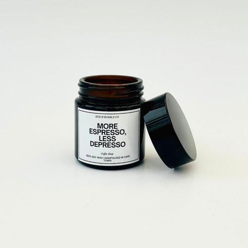 Candle in a black jar with a label reading 'More Espresso, Less Depresso' on a white background