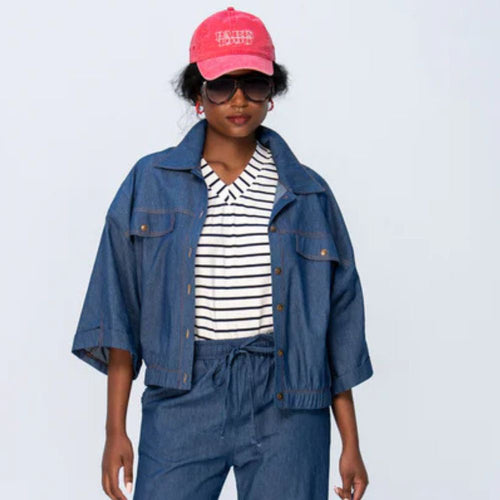 Person wearing a denim outfit with a pink cap on a light gray background