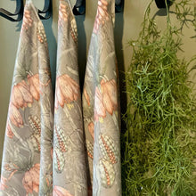 Load image into Gallery viewer, JW Designs tea towels with green aloe flower print hanging on a rack with greenery in the background.
