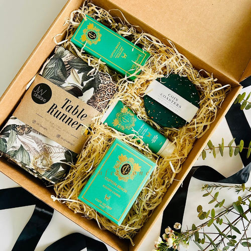 Gift box with decorative items including a table runner and coasters.