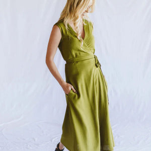 Woman wearing a green wrap dress against a white background