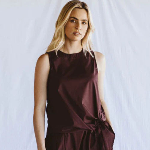 Woman wearing a dark sleeveless top against a light background
