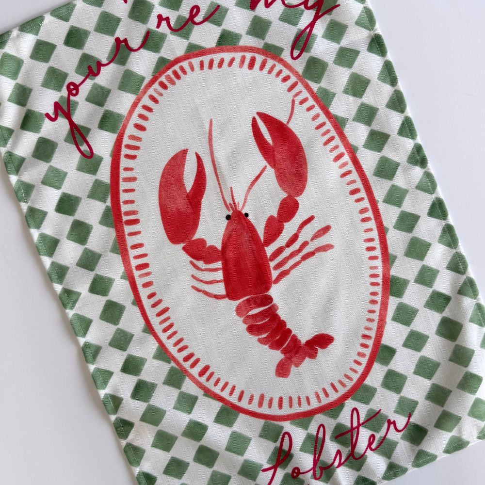 Green & white checkered tea towel with a red lobster design and text on a white background
