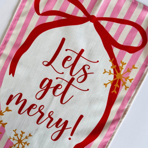 Te Towel with 'Let's get merry!' text and red bow on pink and white striped background