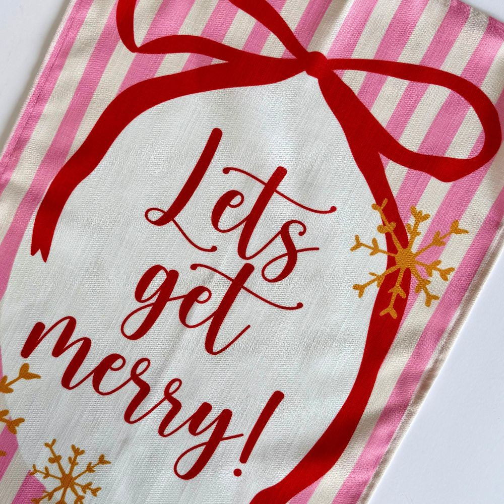 Te Towel with 'Let's get merry!' text and red bow on pink and white striped background