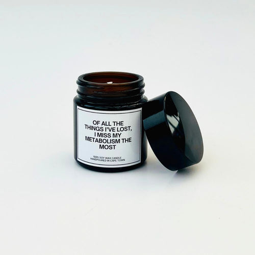 Candle in a black jar with a humorous label about metabolism on a white background