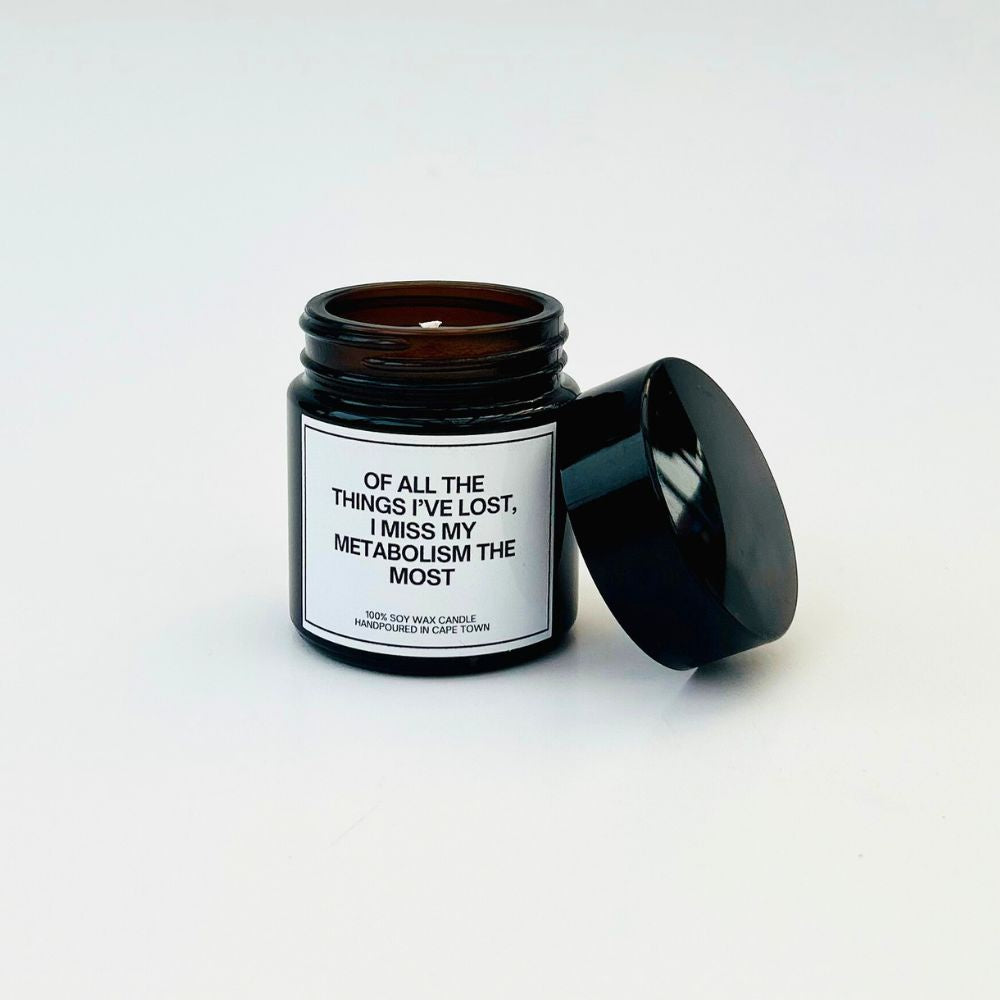 Candle in a black jar with a humorous label about metabolism on a white background
