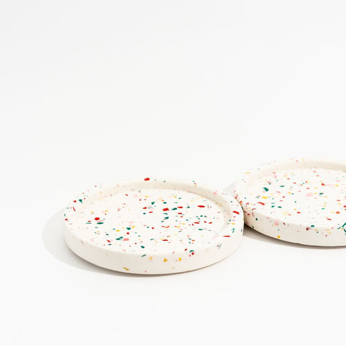 Two round white mini trays with colourful sprinkles on a white background