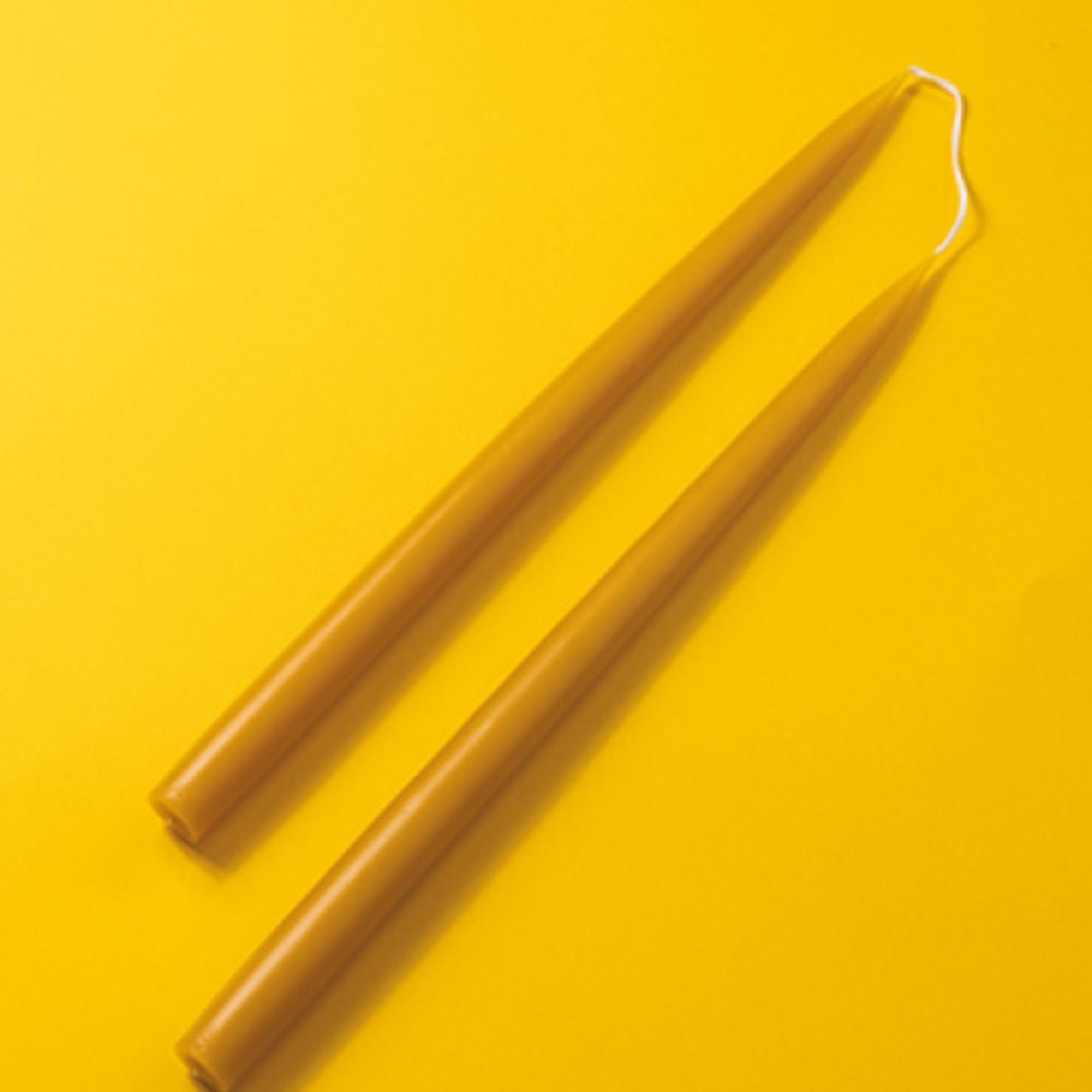 Two yellow candles on a yellow background