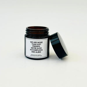 Scented candle in a black jar with a white label with a funny expression about friends on it