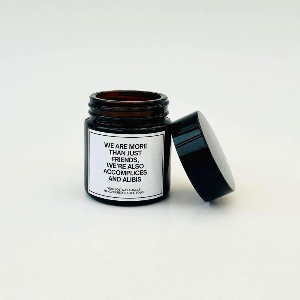 Scented candle in a black jar with a white label with a funny expression about friends on it