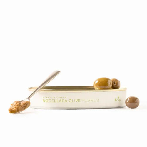 Tin of Nocellara olive hummus with a spoon and olives on a white background