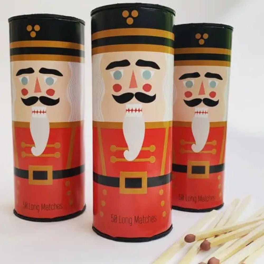 Three cylindrical matchboxes with nutcracker design on a white background