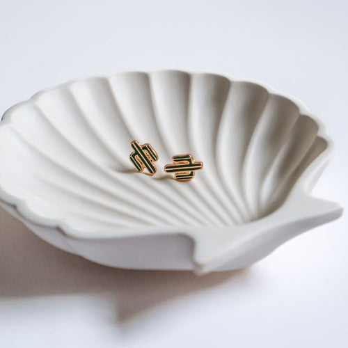 Gold earrings on a white shell-shaped dish