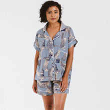 Load image into Gallery viewer, Woman wearing a matching shirt and shorts pyjama set with a blue and white pattern on a plain background
