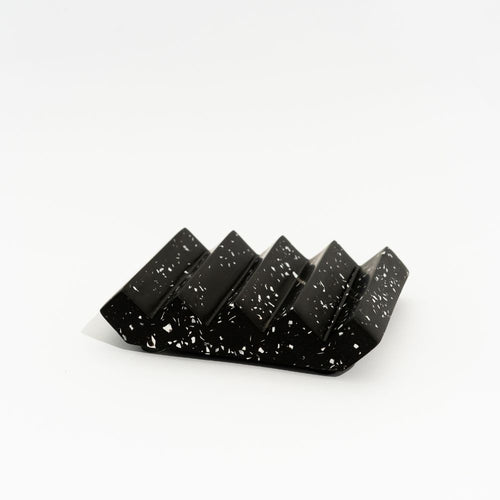 Black soap dish with white speckles on a white background