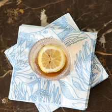 Load image into Gallery viewer, Glass of tea with lemon slices on a blue &amp; white floral-patterned paper napkin on a marble surface
