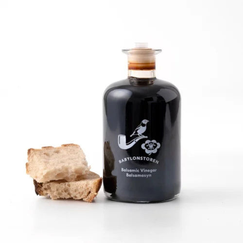Bottle of Babylonstoren Balsamic Vinegar with a piece of bread on a white background