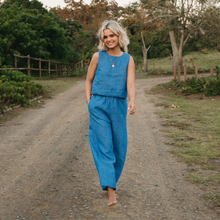 Load image into Gallery viewer, Woman in a blue outfit walking on a dirt path in a natural setting
