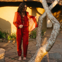 Load image into Gallery viewer, Woman in a red outfit standing under a tree with warm sunlight
