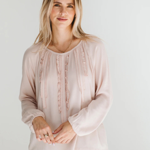 Load image into Gallery viewer, Woman wearing a light pink blouse with ruffled details on a plain background
