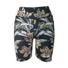 Load image into Gallery viewer, Black activewear shorts with a nature-themed pattern on a white background
