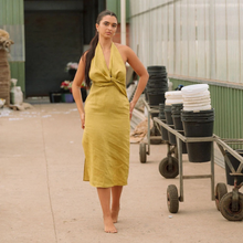 Load image into Gallery viewer, Woman in a yellow dress standing in an outdoor setting with storage containers in the background
