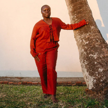 Load image into Gallery viewer, Person wearing a red outfit standing next to a tree
