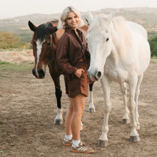 Load image into Gallery viewer, Woman wearing a brown short set standing between two horses in an outdoor setting
