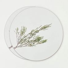 Load image into Gallery viewer, Round white placemat with a green leafy branch design on a light gray background
