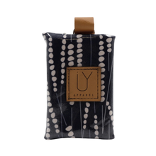 Load image into Gallery viewer, A small fabric pouch with a black and white vertical dotted pattern, featuring a tan leather IY brand patch on the front and a matching tan loop at the top, shown on a plain white background.
