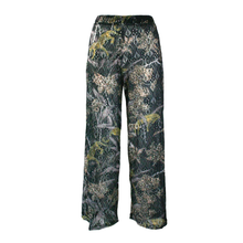 Load image into Gallery viewer, Wide-leg trousers featuring an all-over leopard pattern with green, gray, black, and yellow-green foliage and bird motifs, shown against a plain white background.
