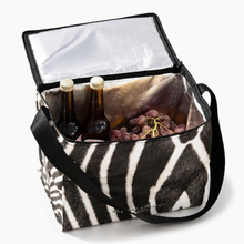 Load image into Gallery viewer, A zebra-print insulated cooler bag with black handles, shown open with a silver interior, containing two bottles and a bunch of grapes, on a white background.
