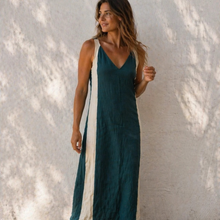 Load image into Gallery viewer, Woman wearing a teal dress against a textured white wall
