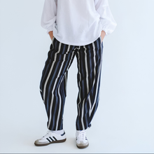 Load image into Gallery viewer, Person wearing black and white striped pants with a plain white background
