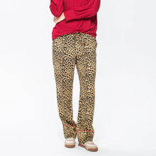 Load image into Gallery viewer, Person wearing red top and leopard print pants on a white background
