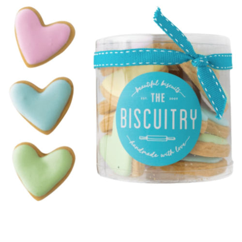 Jar of cookies with a blue ribbon and 'The Biscuistry' label, accompanied by heart-shaped cookies in pastel colors.