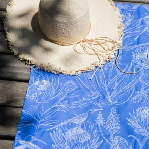 Straw hat on a blue fabric with white floral patterns